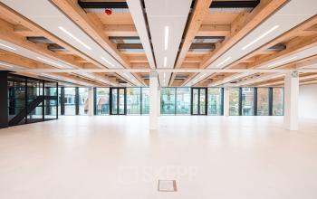 Spacious office to rent at Pieter Cornelisz. Hooftstraat 7 in Amsterdam Center with modern lighting, wooden ceiling elements, and large windows allowing plenty of natural light.