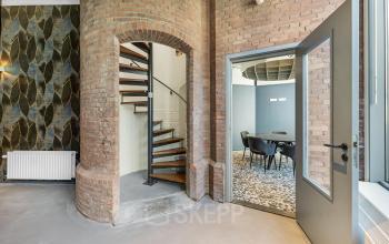 Chic office space with a spiral staircase and a conference room in Amsterdam Center. Ideal for office space rental at Stadhouderskade 55, highlighting a blend of modern and vintage architecture.