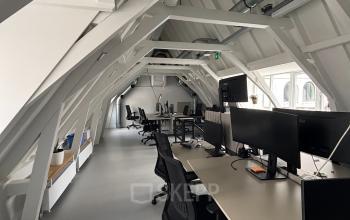 Modern office space in Amsterdam Center, featuring rows of workstations under a spacious, sloped ceiling. Ideal office to rent for collaborative work.