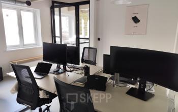 Interior of a furnished office space at Kloveniersburgwal 131K, Amsterdam Center, featuring multiple desks with monitors and chairs for rent.