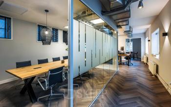 Contemporary office space in Amsterdam Center featuring a glass-walled conference room and modern furnishings, perfect for office space rental at Rapenburgerstraat 173.