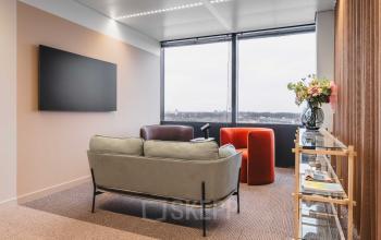 Modern office lounge space in Amsterdam Center, featuring comfortable seating and a large window view. Ideal for office space rental.