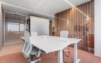 Modern office at Piet Heinkade 55, Amsterdam Center, with white desks and glass partitions, ideal for office space rental.