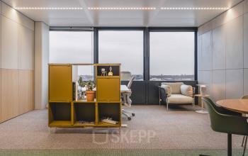 Interior of an office space for rent at Piet Heinkade 55, featuring stylish furniture and large windows with a city view.