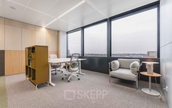 Bright office space with large windows at Piet Heinkade 55, ideal for those seeking an office to rent in Amsterdam Center. Includes a desk, chairs, and storage unit.