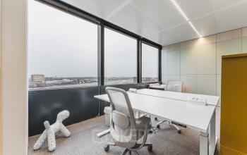 Bright office space featuring large windows and modern furniture with views of Amsterdam Center, perfect for office space rental.