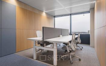 Furnished office space at Piet Heinkade 55, Amsterdam Center, featuring modern workstations with ergonomic chairs and a view through large windows.