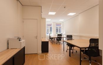 Bright office space at Korte Leidsedwarsstraat 133A 133A, Amsterdam Center featuring wooden floors, office desks with chairs, and a printer. Ideal for rent as a workspace.