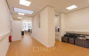 Available office space for rent at Korte Leidsedwarsstraat 133A, Amsterdam Center, featuring a clean interior with natural light and visible workspaces in the background.