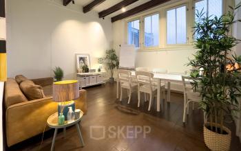 Cozy interior office space at Warmoesstraat 149-151 in Amsterdam Center, featuring a relaxed seating area, wooden floors, and a table for meetings. Ideal for office space rental with a welcoming ambiance.