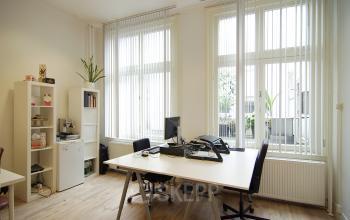 Well-lit office space rental at Warmoesstraat 149 - 151, featuring a tidy desk setup and shelving units, in Amsterdam Center.