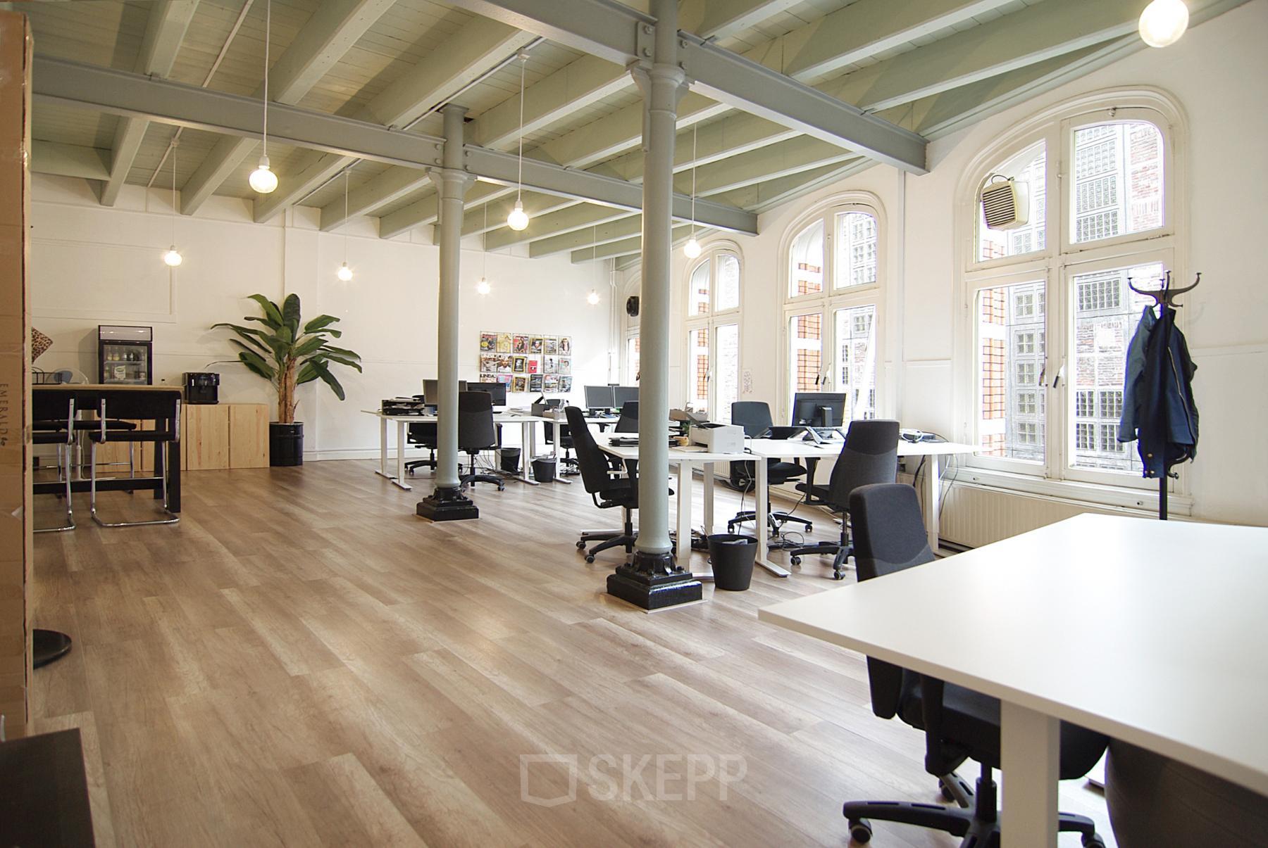 Spacious office space rental at Warmoesstraat 149-151 in Amsterdam Center with modern furniture and large windows.