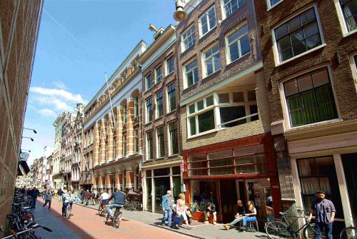 Exterior view of office building located at Warmoesstraat 155, Amsterdam Center, Amsterdam, with people walking and cycling nearby.