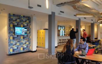 Modern office space rental at Weteringschans 165, Amsterdam Center, with professionals engaged in discussions and working on laptops.