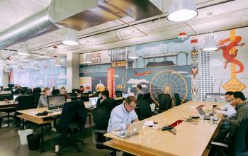 Vibrant Amsterdam Center office space rental at Weteringschans 165, with professionals focused on their work, surrounded by lively wall art and modern furnishings.