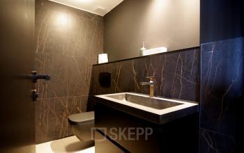 Modern restroom interior with dark walls and sleek fixtures at Kleine Gartmanplantsoen 21, ideal for office space rental in Amsterdam Center.