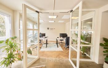 Bright office space at Kleine Gartmanplantsoen 21, Amsterdam Center, featuring glass doors and modern furnishings. Ideal for office space rental with plants enhancing the workspace ambiance.