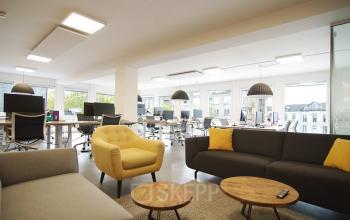 Modern office space at Kleine Gartmanplantsoen 21 featuring stylish furniture and large windows, available as an office to rent in Amsterdam Center.