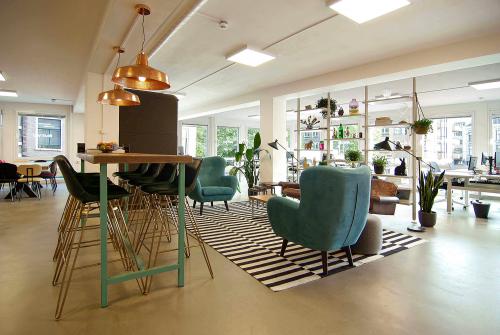 Modern office space with stylish furnishings featuring colorful chairs, high tables, and greenery at Kleine Gartmanplantsoen 21, Amsterdam Center. Ideal for office space rental with a creative and inviting atmosphere.