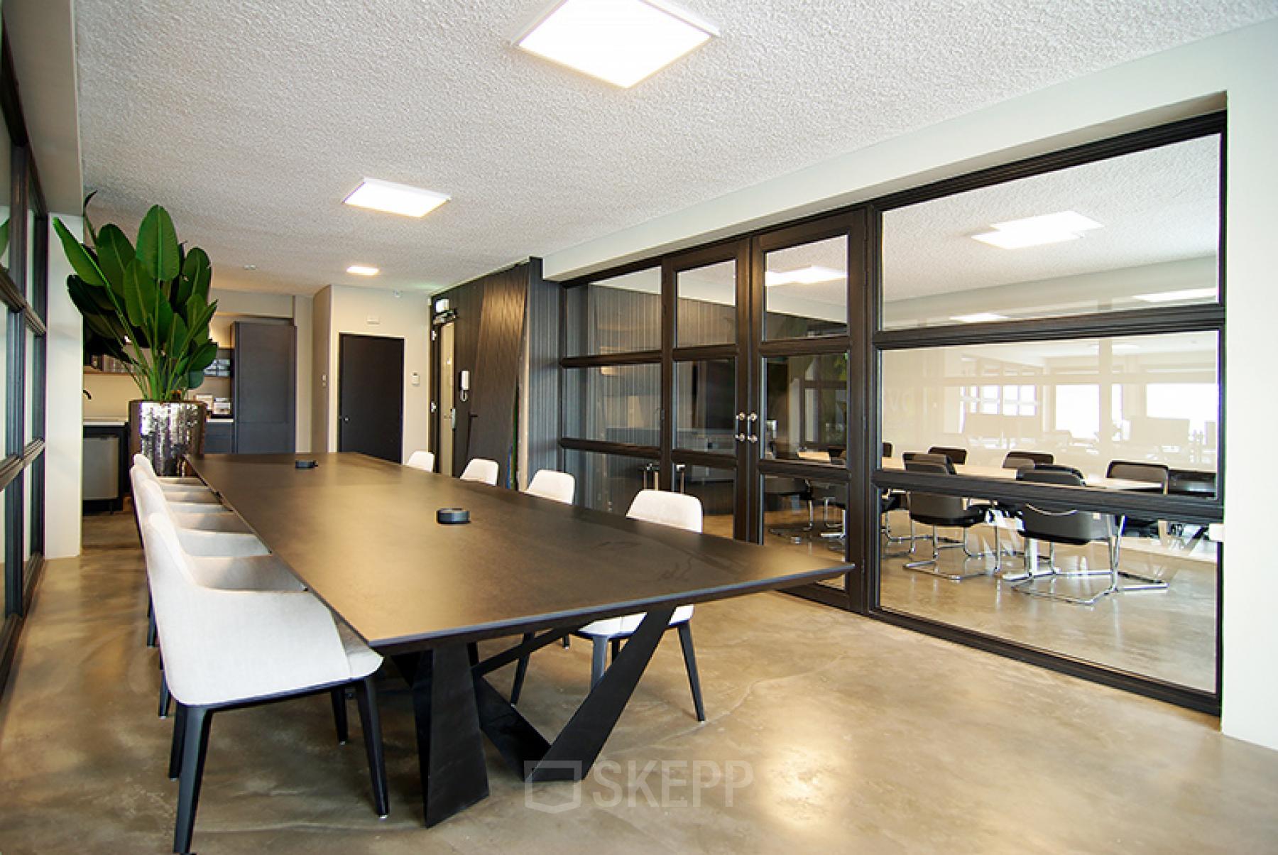 Modern conference room with large table, stylish chairs, and indoor plants at Kleine Gartmanplantsoen 21 in Amsterdam Center for office space rental.