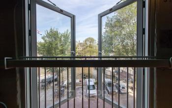 View through open windows of an office located at 's-Gravenhekje 1A, Amsterdam Center, showing a serene city and canal scene outside.