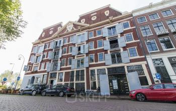 Exterior of historic office building at 's-Gravenhekje 1A in Amsterdam Center with cars parked in front.