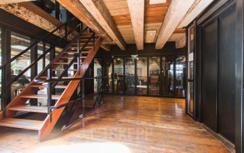 Interior view of the office space at 's-Gravenhekje 1A, Amsterdam Center, showing wooden flooring, an open staircase, and glass partitions for private workspaces.
