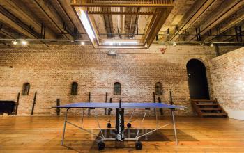 Stylish, spacious office to rent at 's-Gravenhekje 1A, Amsterdam Center featuring brick walls and a ping pong table under a wooden ceiling.