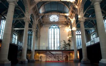 Spacious interior of a historic building at Zuiderkerkhof 72, Amsterdam Center, with high ceilings and large arched windows, ideal for office space rental.