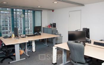 Modern workspace in the office to rent at Zuiderkerkhof 72, Amsterdam Center, featuring multiple desks with computers and large windows for natural light.