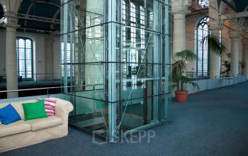 Spacious office to rent with a modern elevator and cozy seating area, located at Zuiderkerkhof 72 in Amsterdam Center. Large windows provide natural light enhancing the open floor plan.