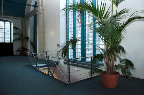 Spacious interior area with large windows and potted plants in an office to rent at Zuiderkerkhof 72, Amsterdam Center. Bright natural light floods the space, creating a welcoming atmosphere.