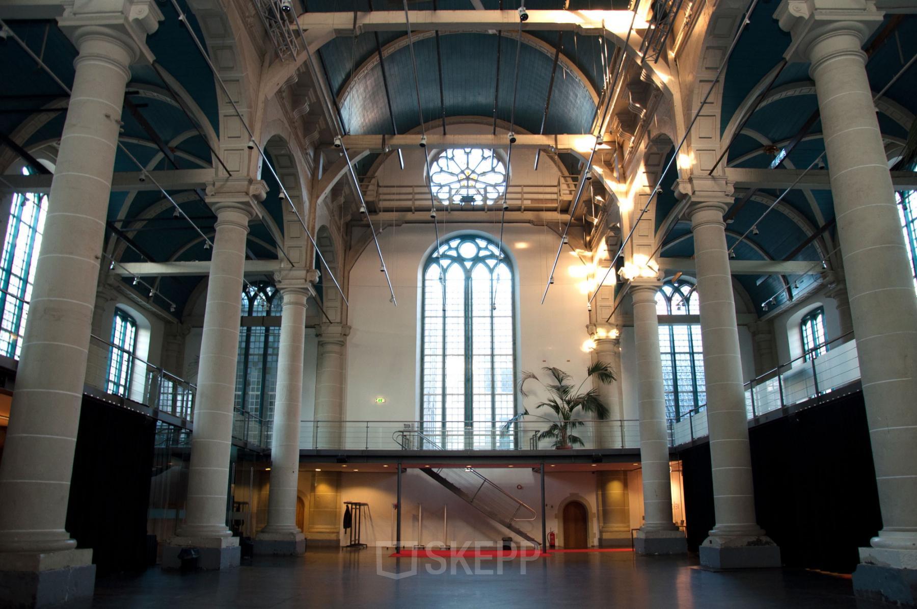 Spacious interior of a historic building at Zuiderkerkhof 72, Amsterdam Center, with high ceilings and large arched windows, ideal for office space rental.