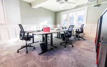 Furnished office space with multiple desks and chairs, located in Amsterdam Center. Ideal for office space rental with natural light and modern decor.