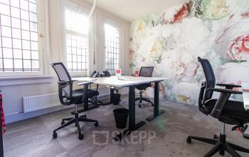 Bright office space with modern desks, ergonomic chairs, and a floral feature wall, perfect for rent office space in Amsterdam Center.