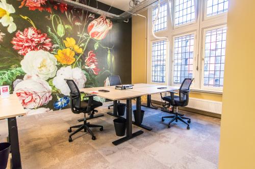 Bright office space for rent in Amsterdam Center, featuring modern furnishings and large windows. Ideal for business activities against a vibrant floral mural.