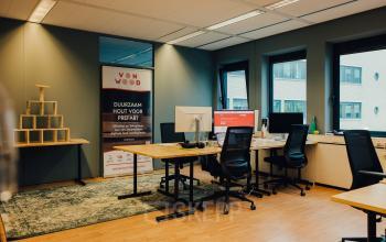 Furnished office space for rent at IJsbaanpad 2, Amsterdam De Schinkel with work desks, chairs, and natural light from large windows.