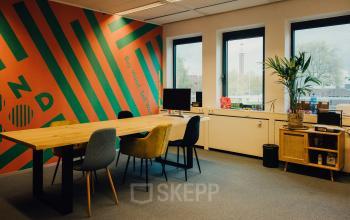 Bright, colorful office space at IJsbaanpad 2, Amsterdam De Schinkel, with a large table, modern chairs, and a vibrant wall mural, ideal for office space rental.