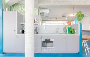 Modern pantry area in the office located at Generaal Vetterstraat 77e, Amsterdam De Schinkel, featuring sleek cabinetry, plants, and coffee machine.