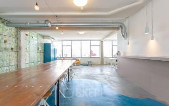 Modern office space in Amsterdam De Schinkel with long wooden table, chairs, and large windows for natural light, located at Generaal Vetterstraat 77e
