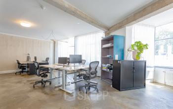 Modern office to rent at Generaal Vetterstraat 77e in Amsterdam De Schinkel, featuring open workspaces with desks, chairs, and storage units, illuminated by large windows.