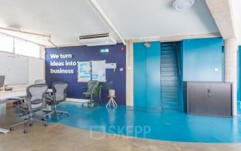 Office space rental at Generaal Vetterstraat 77e, Amsterdam De Schinkel, with modern furnishings, blue walls, and ergonomic chairs. A motivational quote is displayed on the wall.