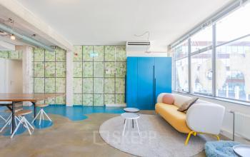 Modern office space with a vibrant design located at Generaal Vetterstraat 77e in Amsterdam De Schinkel, featuring colorful furnishings, large windows, and a unique wall pattern.
