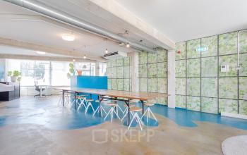 Modern open workspace with long wooden table, stools, and large windows at Generaal Vetterstraat 77e, Amsterdam De Schinkel, available for office space rental.
