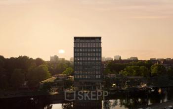 Exterior view of the office building located at Rijnsburgstraat 9-11 9-11 in Amsterdam De Schinkel, Amsterdam, seen from across a canal with the sun setting in the background.