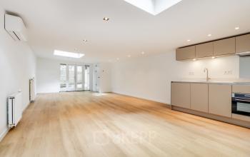 Bright and spacious office to rent at Schinkelkade 44, Amsterdam De Schinkel, featuring a sleek wooden floor and modern kitchenette, ideal for business activities.