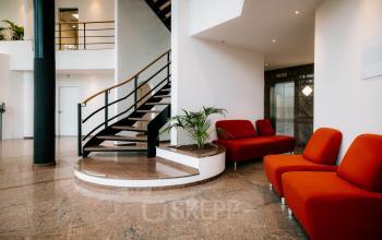 Modern office space with red seating, a spiral staircase, and a bright, welcoming atmosphere at Overschiestraat 182, Amsterdam De Schinkel. Ideal for office space rental.