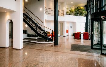 Spacious and bright office interior at Overschiestraat 182, featuring a modern staircase and seating area, ideal for office space rental.