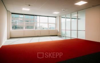 Spacious and sunlit office to rent at Overschiestraat 182, Amsterdam De Schinkel featuring large windows and carpeted floors, ideal for office space rental.