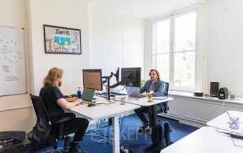 Two professionals working at desks with computers in a furnished office at Herengracht 420, Amsterdam Canal Belt, available for office space rental.